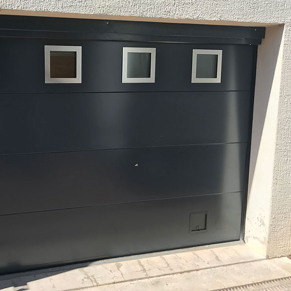 Porte de garage sectionnelle FAME Modèle LA VERTICALE avec hublots carré et trappe pour chat Chantier CHAPONOST